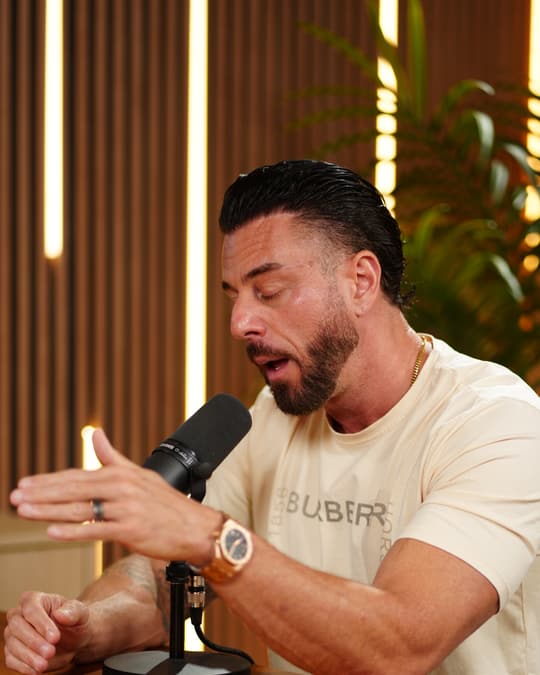 A guest speaking into a desk microphone in the studio.